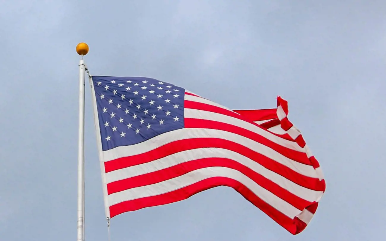 usa-flag-waving-on-white-metal-pole-15503423